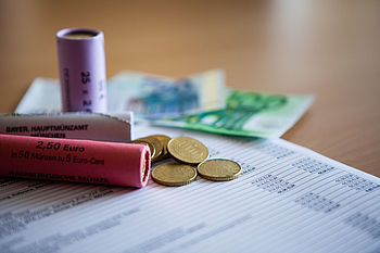 Münzrollen, Kleingeld und Geldscheine auf einer Abrechnung © HTW Berli